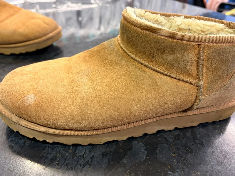 A sheepskin boot before cleaning, faded and worn with a soiled sole